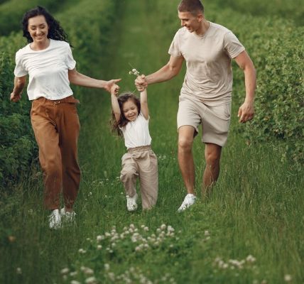 Joyful family enjoying a fun day outdoors in a green field, epitomizing togetherness and happiness.