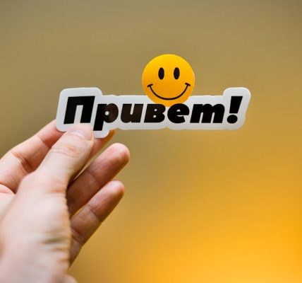 Hand holding a sticker with "привет!" and a smiley face.