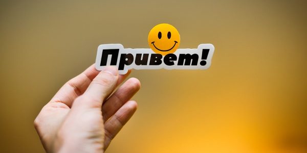 Hand holding a sticker with "привет!" and a smiley face.